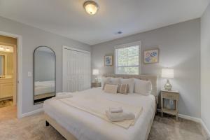 een witte slaapkamer met een groot bed en een spiegel bij Pondside at Sweetoak in Columbia