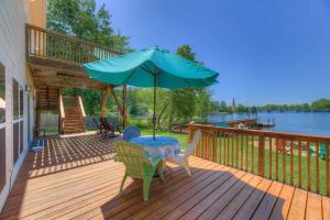 une terrasse en bois avec une table et un parasol dans l'établissement Luxurious Stay on Lake Murray, à Lake Murray Shores