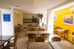 un restaurante con mesas, sillas y paredes amarillas en Saint Patrick Praia Hotel en Maceió