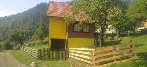 una casa amarilla con una valla delante de ella en Vikendica Studenac, en Bajina Bašta