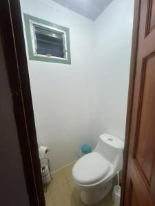 baño blanco con aseo y ventana en Churubusco Trailer en Vara Blanca