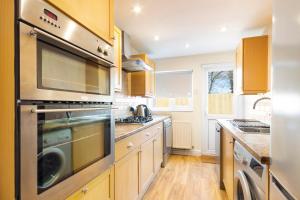a kitchen with stainless steel appliances and wooden cabinets at Detached 4-Bed House near Heathrow in Egham