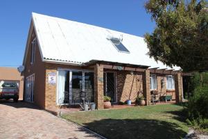 una piccola casa di mattoni con il tetto di lamiera di Whales, Waves and Walks - Beach Cottage a De Kelders