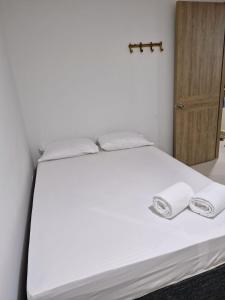 um quarto com uma cama branca e toalhas em Acogedor apartamento en Santa Marta em Santa Marta