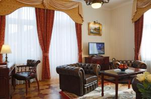 a living room with leather furniture and a television at Hotel Vila Livia in Karlovy Vary