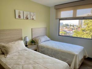 a bedroom with two beds and a window at Lovely 3-bedroom rental unit with free parking in Guatemala