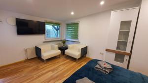 a room with a bed and two chairs and a television at Bungalow an der Tanne mit überdachter Terrasse in Düsseldorf