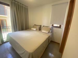 Schlafzimmer mit einem weißen Bett und einem Fenster in der Unterkunft Vila beija-flor prime / apt 02 in Mucugê