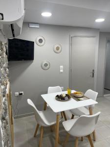 Meraki house of kalymnos Apartments في كاليمنوس: غرفة طعام مع طاولة بيضاء وكراسي بيضاء