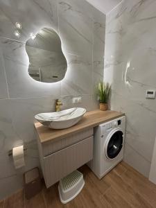 a bathroom with a sink and a washing machine at Apartament Holiday Mini Gold in Rewal