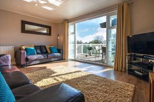 een woonkamer met een bank, een tv en een balkon bij Isis Lakes 50, Natterjack Lodge - P in South Cerney