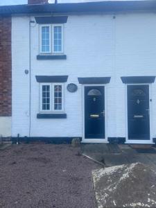 a white house with two blue doors and windows at THE ENCHANTED COTTAGE in Rolleston