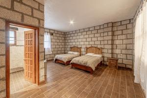 een slaapkamer met 2 bedden in een bakstenen muur bij Rancho Santa Sofía in El Santuario