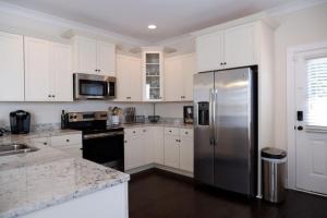 a kitchen with white cabinets and a stainless steel refrigerator at The Garnet Door Bungalow in Columbia