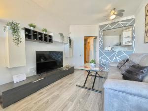 ein Wohnzimmer mit einem Sofa und einem TV in der Unterkunft La Colina - Moderno y acogedor estudio vista mar in Torremolinos