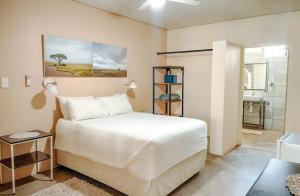 een slaapkamer met een groot wit bed en een badkamer bij Olienhoff Guesthouse in Otavi