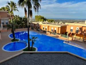 a large blue swimming pool with palm trees and buildings at Cosy home / vue mer / vue montagne / 4 voyageurs in Muntanya la Sella