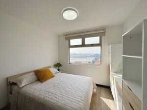 a white bedroom with a bed and a window at Contemporary 3 Bedroom APT with free parking in Guatemala