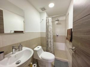 a bathroom with a white toilet and a sink at Contemporary 3 Bedroom APT with free parking in Guatemala
