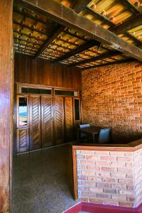 Habitación vacía con paredes de ladrillo y techos de madera. en Pousada Cia do Peixe, en Marataízes