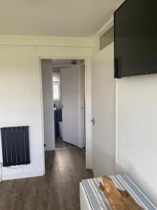 a room with white walls and wooden floors and a door at 95 Sundowner, Hemsby, Norfolk in Hemsby
