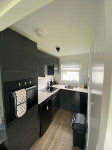 a kitchen with black cabinets and a sink at 95 Sundowner, Hemsby, Norfolk in Hemsby