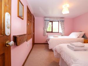 2 camas en una habitación con paredes rosas y ventana en The Stable, en Crosby Ravensworth