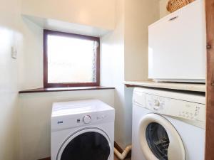 uma lavandaria com uma máquina de lavar roupa e uma janela em The Stable em Crosby Ravensworth