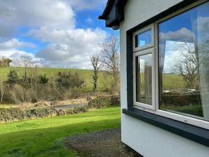 une fenêtre d'une maison avec vue sur un champ dans l'établissement The Lodge-Cozy and serene home, à Cavan