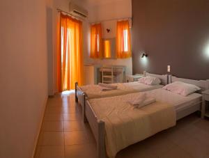 ファラサルナにあるKalami Roomsのオレンジ色のカーテンが備わる客室のベッド2台