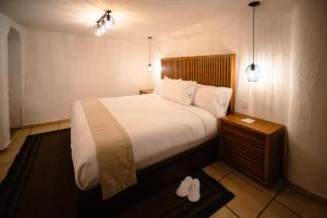 een slaapkamer met een bed met witte lakens en kussens bij BOTANIQ HOTEL BOUTIQUE in Valle de Bravo