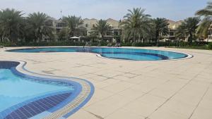 a large swimming pool with palm trees and a building at Luxury villa 4 bedroom with pool access in Ras al Khaimah