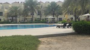 una piscina con sedie e un tavolo accanto a un edificio di Luxury villa 4 bedroom with pool access a Ras al Khaimah