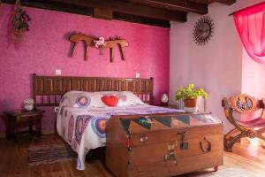 a bedroom with a bed with a dresser and a pink wall at Hostal-Resturante La Moruga in Hortigüela