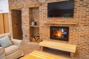a living room with a fireplace with a tv on a brick wall at The Kennels in Hexham