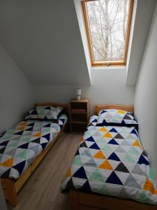 two beds in a small room with a window at Biały Bocian in Stegers