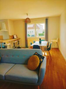 ein Wohnzimmer mit einem blauen Sofa und einem Tisch in der Unterkunft L'étape Nuitonne - Gîte avec jardin pour 6 personnes in Nuits-Saint-Georges