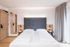 a bedroom with a large white bed with two tables at Hotel Wieser in Campo di Trens