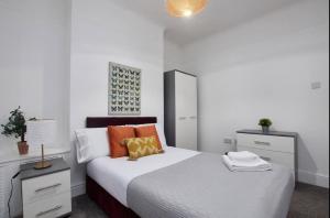 Habitación blanca con cama y espejo en Spacious 4 bedroom house in Wallasey for 7 people with parking BridgeCity, en Wallasey