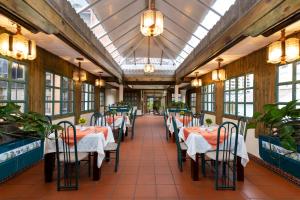 a restaurant with tables and chairs in a room with windows at Hotel NASS Pinar del Lago in Cuenca