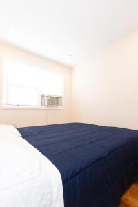 a white room with a bed with a blue blanket at Astonishing 3-Bed Apt Close to NYC in Jersey City