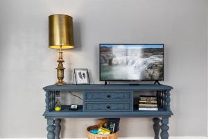 a television on a blue console table with a lamp at #StayInMyDistrict Historic Charm in Twin Falls