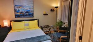 a bedroom with a bed with a yellow pillow and a chair at Kokomo INN Bed and Breakfast Ottawa-Gatineau's Only Tropical Riverfront B&B on the National Capital Cycling Pathway Route Verte #1 - for Adults Only - Chambre d'hôtes tropical aux berges des Outaouais BnB #17542O in Ottawa