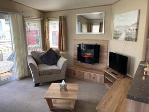 a living room with a couch and a television with a fireplace at Bluebell in Ferndown