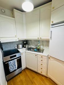 uma cozinha com armários brancos, um lavatório e um frigorífico em Laivurinkatu 35 em Helsinque
