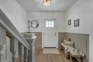 a white hallway with a staircase and a mirror at Charming Retreat - Close to Zoo and Downtown in Omaha
