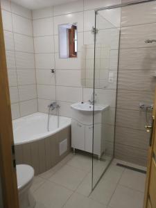 a bathroom with a tub and a toilet and a sink at Biró apartmanház Sármellék in Sármellék