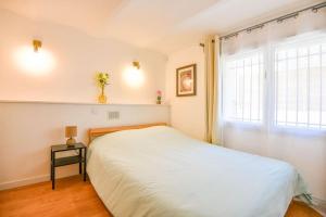 1 dormitorio con cama blanca y ventana en Bas de villa près du stade Vélodrome en Marsella