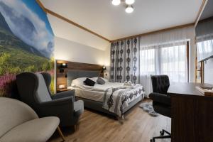 a hotel room with a bed and two chairs at Willa Nosalowa Dolina in Zakopane