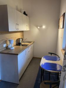 eine kleine Küche mit weißen Schränken und blauen Stühlen in der Unterkunft Appartement Nr. 37 in Oberaudorf